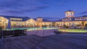 A resort with a large pool, wooden deck, and a tower structure.