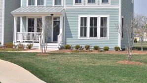 A two-story house with a front porch, a small entryway, and a well-maintained lawn.