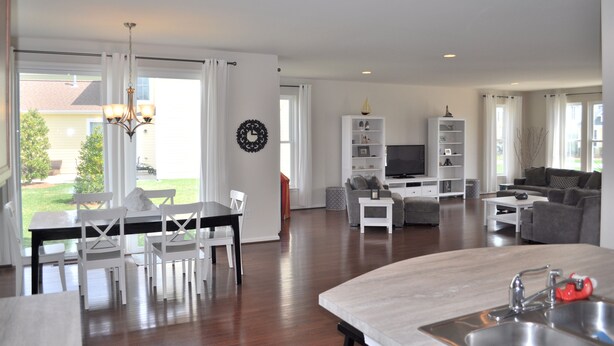 A spacious living area with a dining table, chairs, a sofa, and a TV.