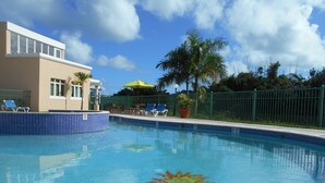A swimming pool with clear blue water, a no diving sign, and lounge chairs.