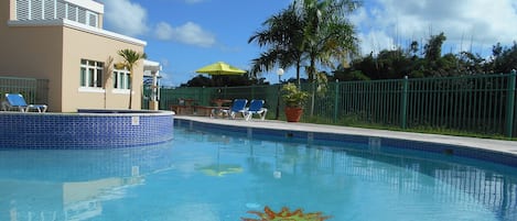 A swimming pool with clear blue water, a no diving sign, and lounge chairs.