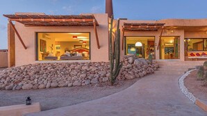 Una casa moderna con un patio, un jardín de cactus e interiores bien iluminados.