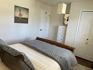 A bedroom with a bed, a white dresser, a door, and a painting on the wall. - In an Upscale Neighborhood, Stunning sunset views! (Santa Rosa)