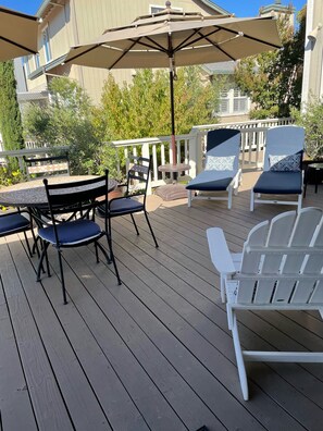 A wooden deck with outdoor furniture including a table and chairs, a large umbrella, and a railing. - In an Upscale Neighborhood, Stunning sunset views! (Santa Rosa)