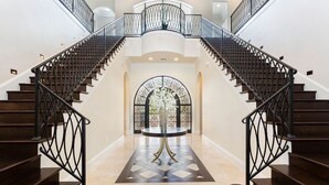 Una imponente escalera con una mesa redonda central y un arco decorativo.