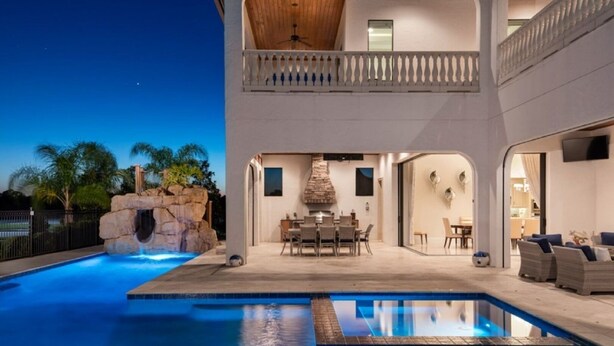 Una casa moderna con piscina, zona de comedor exterior y balcón.