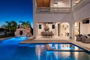 Ein modernes Haus mit Pool, Essbereich im Freien und einem Balkon.