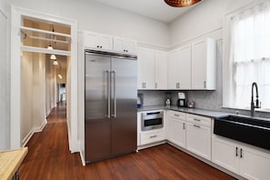 Una cocina moderna con armarios blancos, electrodomésticos de acero inoxidable y piso de madera.