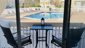 A balcony with a pool, chairs, and a table. - One of SPC's most booked units! Poolfront! Brand NEW renovation!  (Destin)