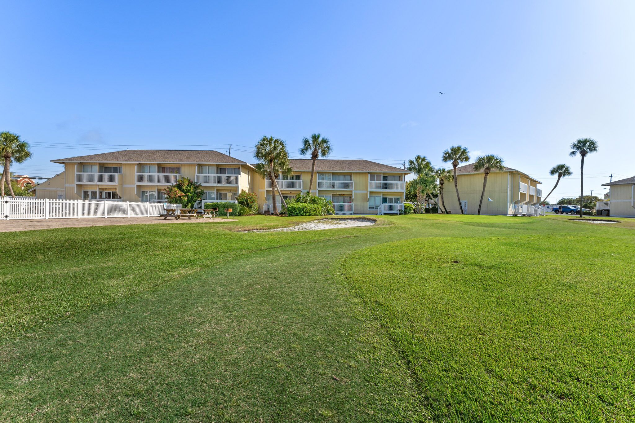 A hotel with multiple floors, a fenced courtyard, and palm trees.