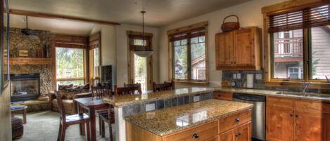 A spacious kitchen with granite countertops, wooden cabinets, and a large island.