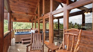 Eine Holzterrasse mit Whirlpool, Holzstühlen und einem Tisch.