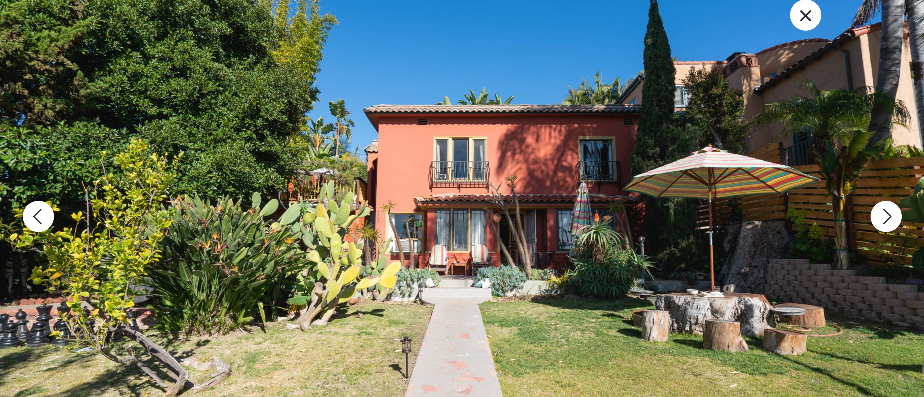 Une maison à l’extérieur rouge, avec un porche à l’avant et un chemin menant à l’entrée.
