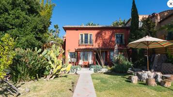 Une maison à l’extérieur rouge, avec un porche à l’avant et un chemin menant à l’entrée.