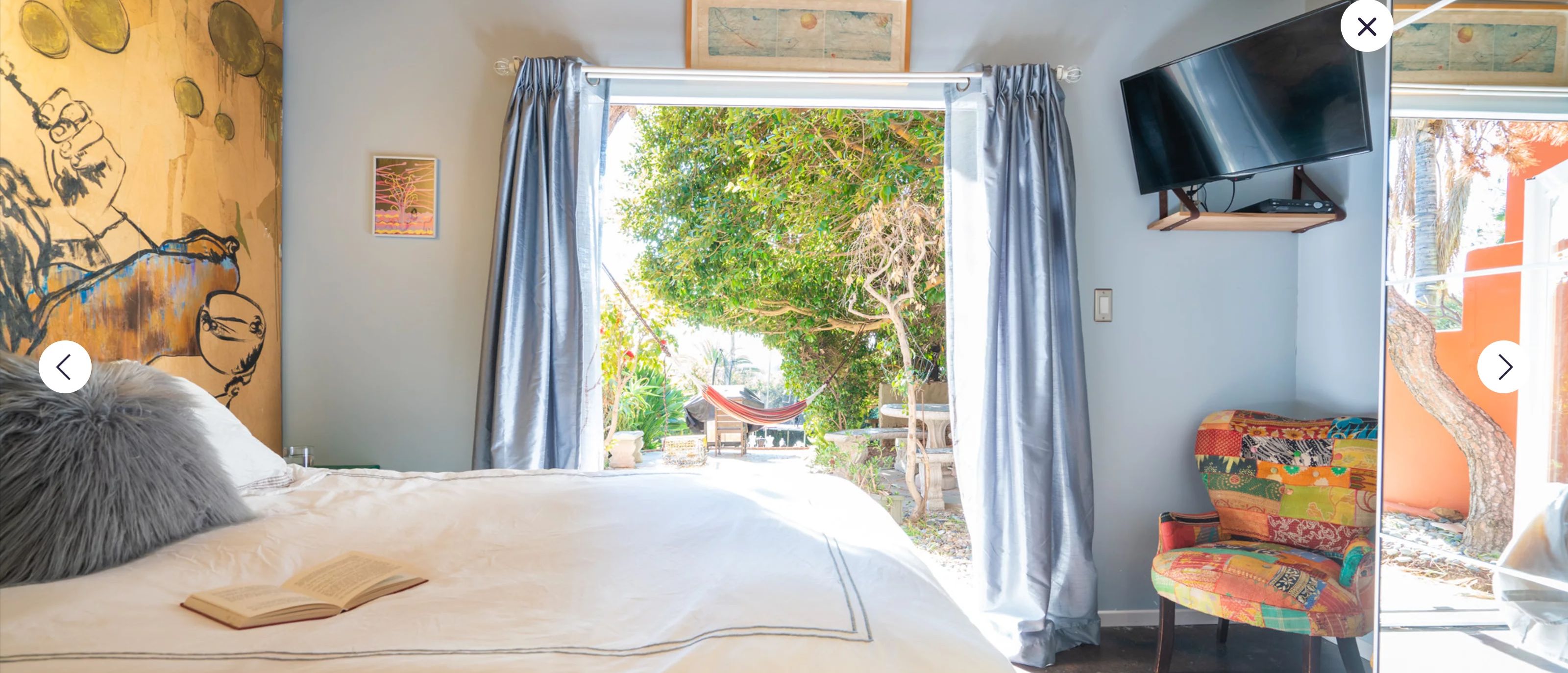 Un dormitorio con cama, televisión, una silla y vistas al exterior.