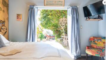 Une chambre avec un lit, une télévision, une chaise et une vue sur l’extérieur.