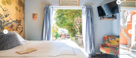 Un dormitorio con cama, televisión, una silla y vistas al exterior.