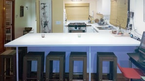 Een keuken met een centraal eiland, krukken, een fornuis en een spoelbak.