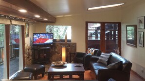 Een woonkamer met een stenen openhaard, een leren bank en een televisie.