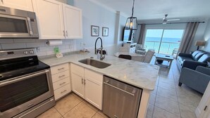 A modern kitchen with stainless steel appliances, a large island with a sink, and a dining area with a view.