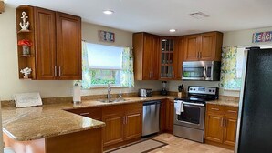 A kitchen with wooden cabinets, granite countertops, stainless steel appliances, and a large island. -  Closest To Beach Main House & Separate Villa 4 Bdrm , Huge Pool. Walk To Beach (Naples)