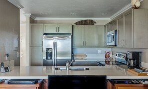 Een moderne keuken met een roestvrijstalen koelkast, een dubbele spoelbak en een magnetron.