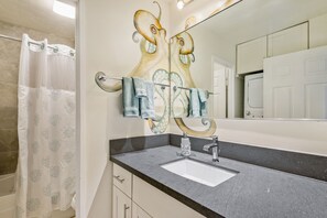 A bathroom with a large mirror, a sink, and a shower curtain.