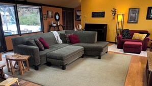 A living room with a sectional sofa, a small wooden table, and a red chair. - Immaculate, warm, inviting with WOW water views! You'll wish you lived here! (Port Angeles)