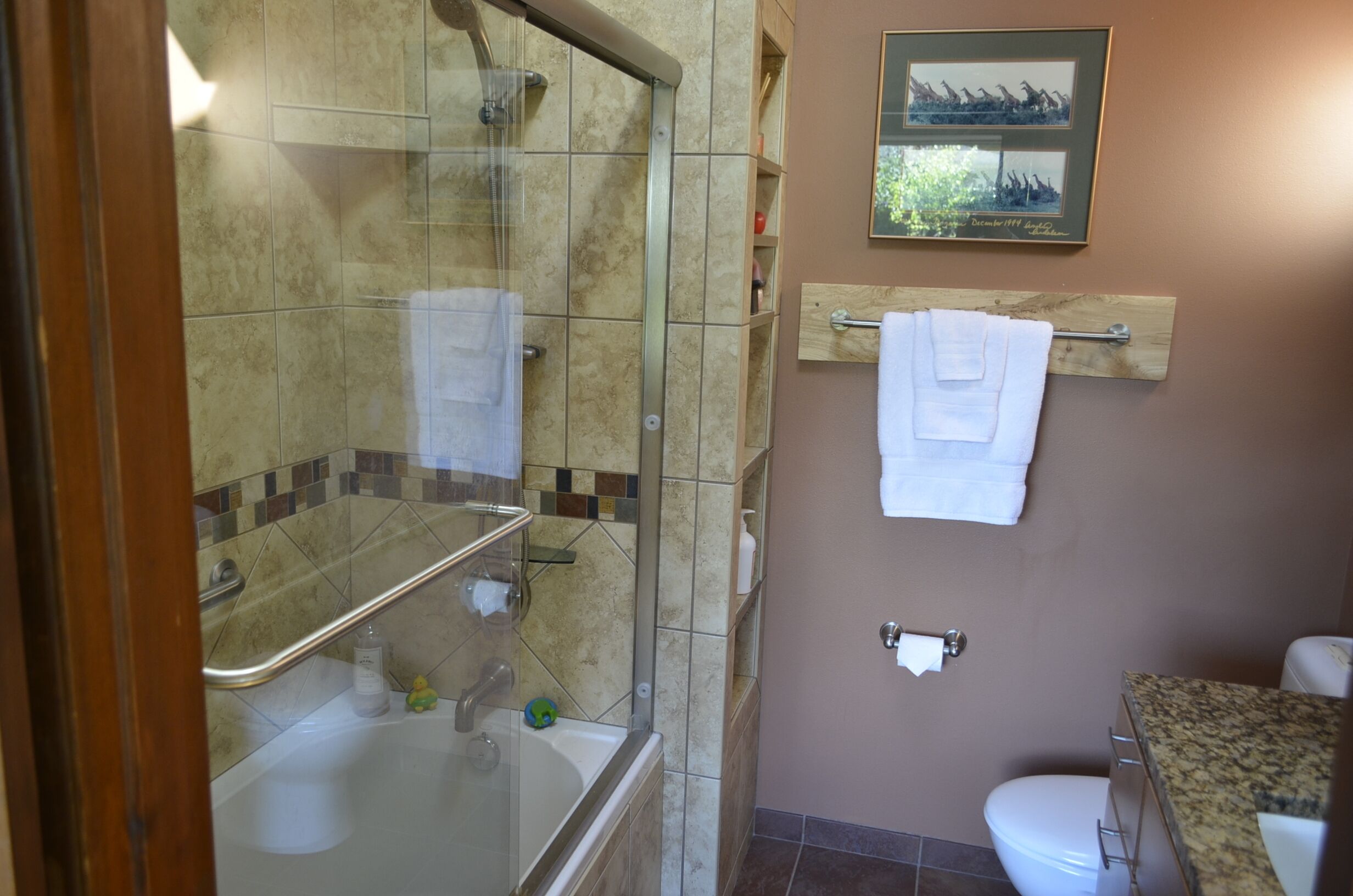 A bathroom with a glass shower enclosure, a bathtub, a toilet, and a towel rack.