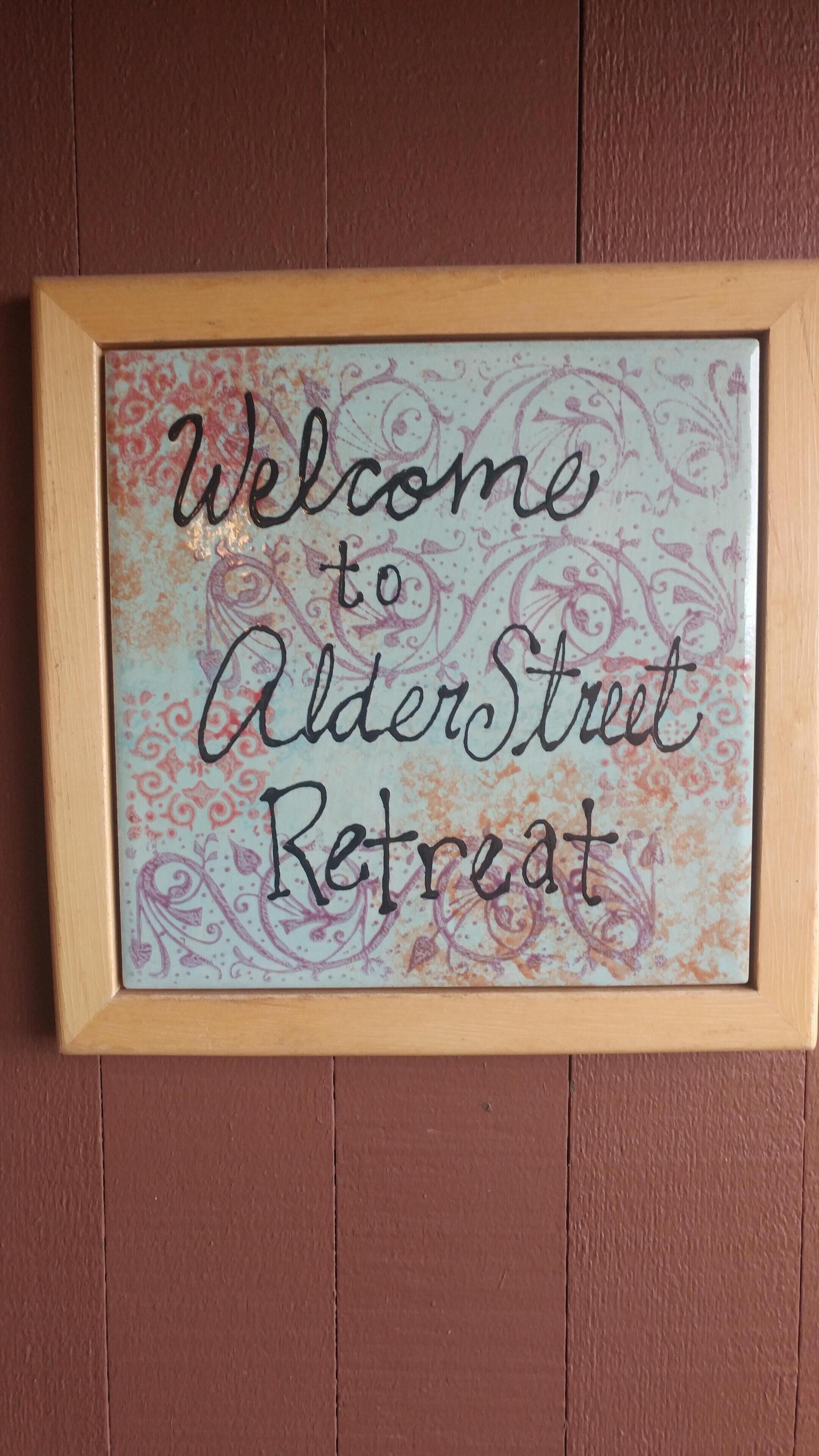 Une pancarte encadrée portant l’inscription : « Bienvenue à AlderStreet Retreat ».