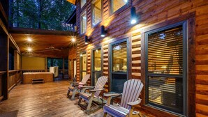 Una baita di legno con veranda, ampie finestre e posti a sedere all'aperto.