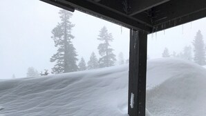 A snow-covered outdoor area with a wooden bench and a railing.