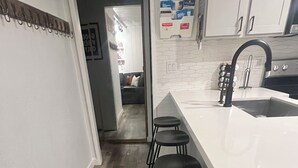 A modern kitchen with a white countertop, black stools, and a black faucet.