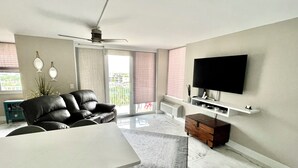 A modern living room with a sofa, TV, and a ceiling fan.