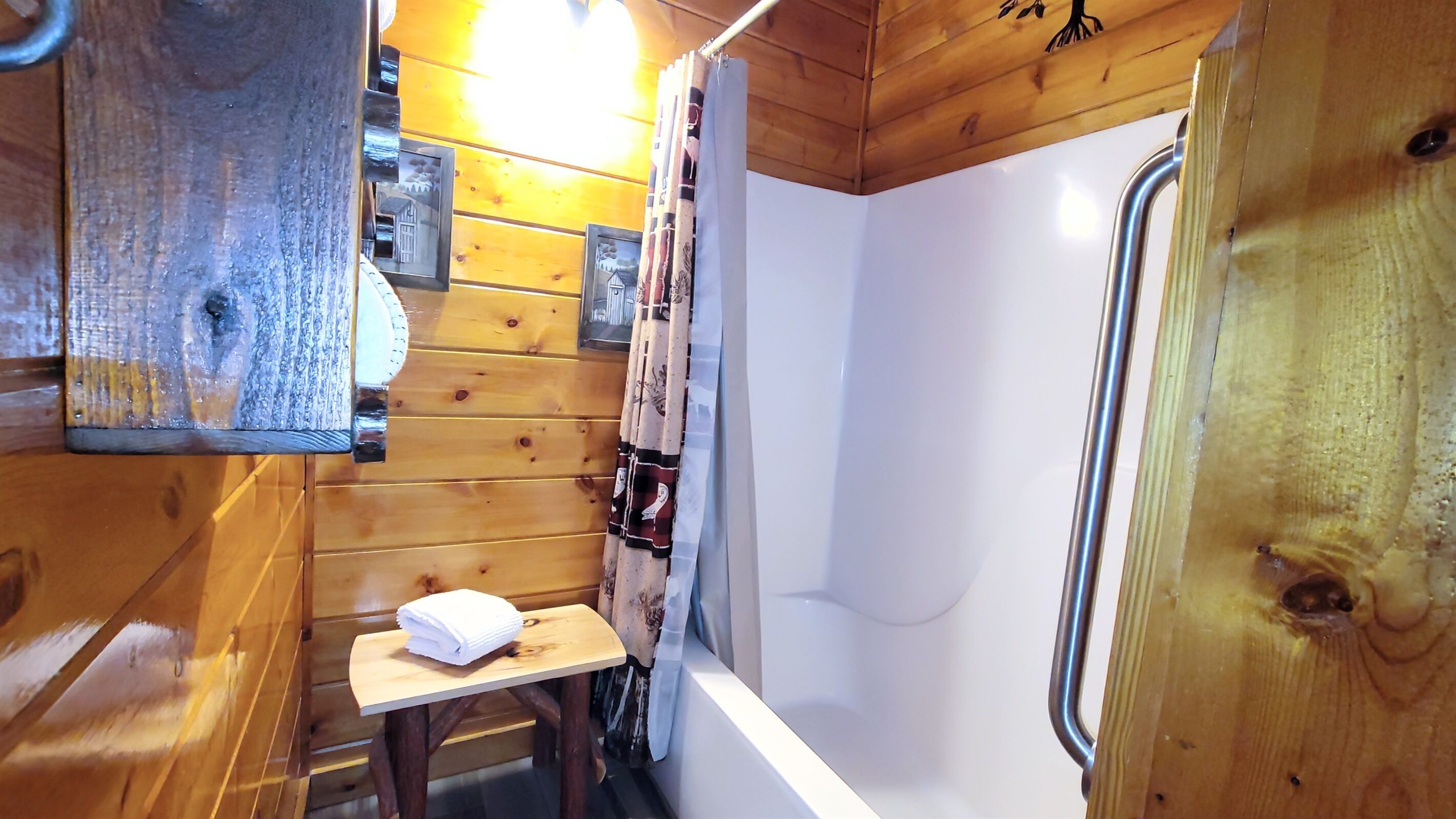 A wooden cabin bathroom with a shower, a small table with a towel, and wooden walls.