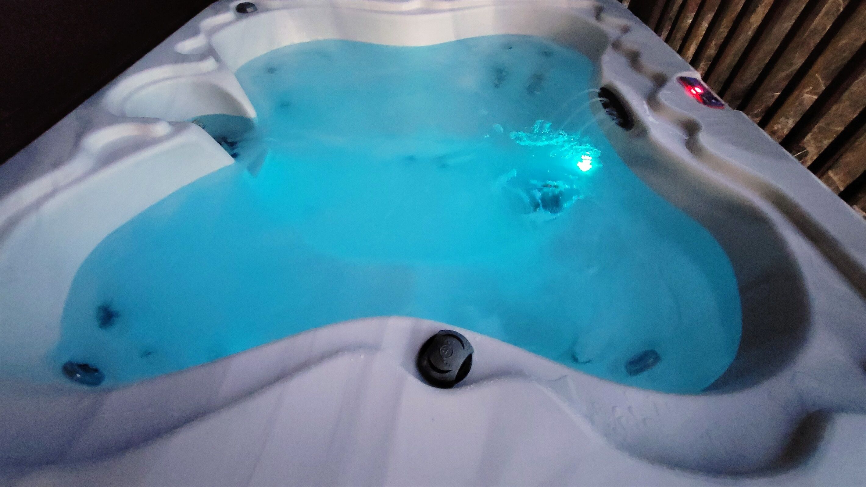 A hot tub with a blue light, a drain, and a control knob.