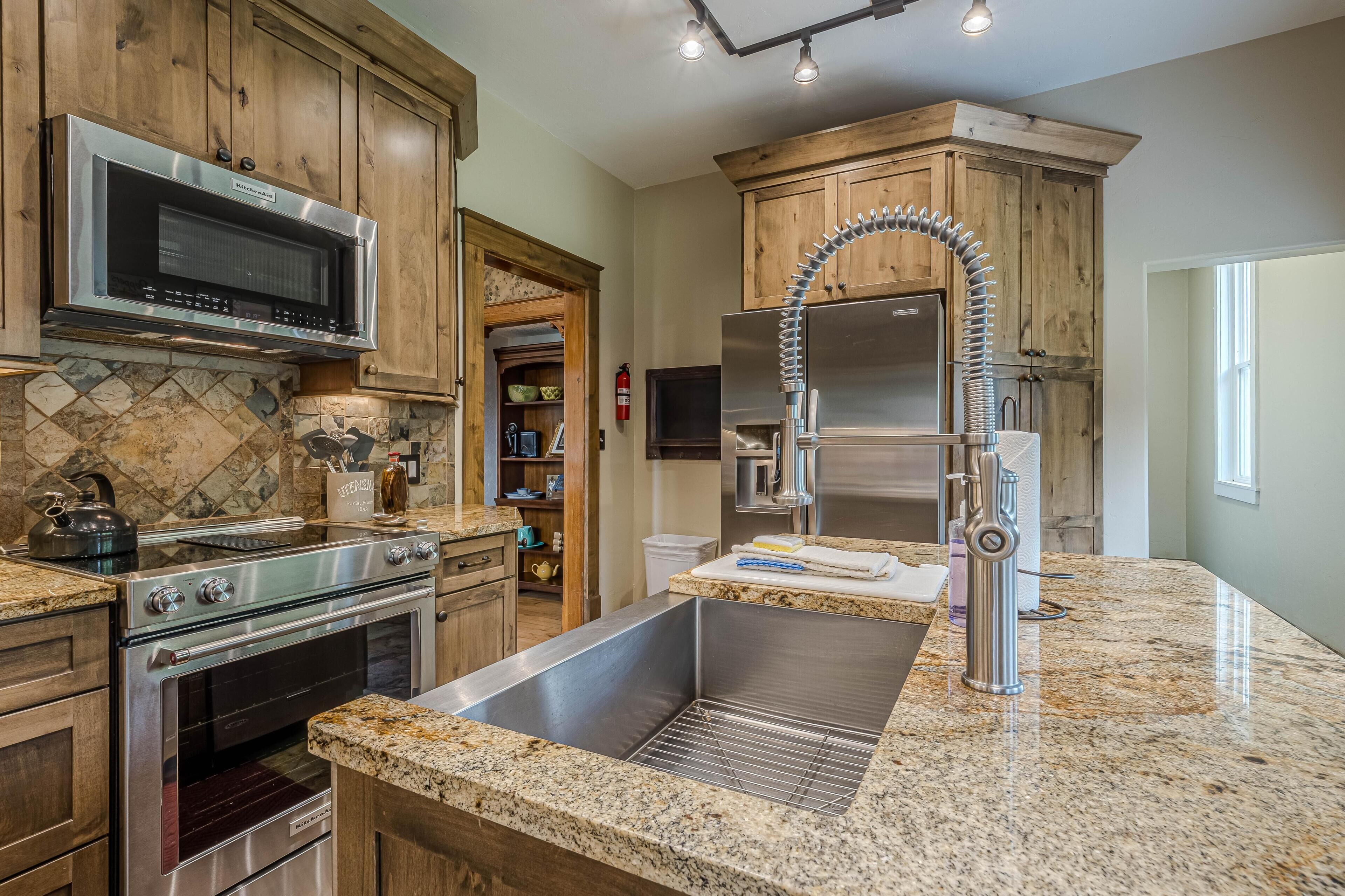 A kitchen with granite countertops, stainless steel appliances, wooden cabinets, and a built-in oven.