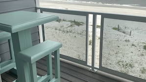Una terraza de madera con mesa y banco que da a una playa.