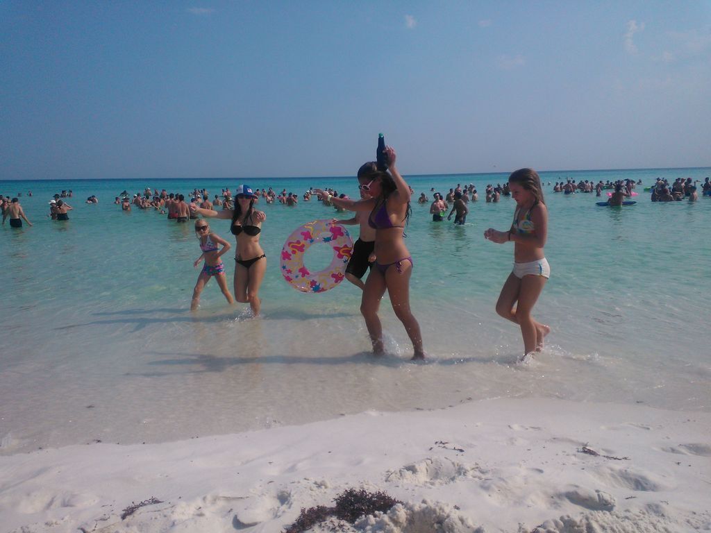 Une plage bondée, avec des gens dans l’eau et sur le sable.