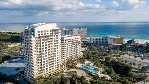 A high-rise hotel with multiple floors, a swimming pool, and a view of the ocean.