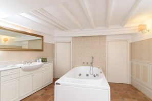 Un bagno con una vasca da bagno ampia, un lavandino e uno specchio.