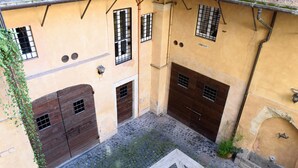 Ein Innenhof mit Kopfsteinpflaster, zwei Holztüren und einem kleinen Brunnen.