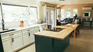 Una cocina moderna con una isla central, armarios blancos y un amplio ventanal que proporciona luz natural.