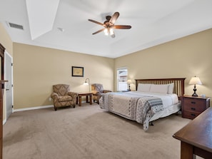 A bedroom with a bed, two chairs, a nightstand, a lamp, a ceiling fan, and a window. - Velo III: BBQ, Fire Pit & Dog-Friendly Retreat (Fruita)