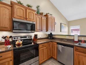 A kitchen with wooden cabinets, a stainless steel stove, a microwave, and a dishwasher. - Velo III: BBQ, Fire Pit & Dog-Friendly Retreat (Fruita)