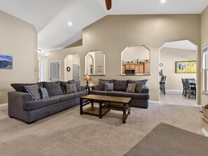 A living room with a sectional sofa, a coffee table, and a dining area with chairs and a table.