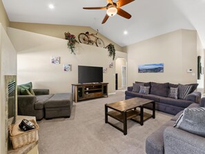 A living room with a sofa, a coffee table, a television, and a ceiling fan. - Velo III: BBQ, Fire Pit & Dog-Friendly Retreat (Fruita)