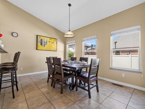 A dining area with a table set for four, surrounded by chairs, a pendant light, and a painting on the wall. - Velo III: BBQ, Fire Pit & Dog-Friendly Retreat (Fruita)
