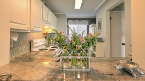 A kitchen with white cabinets, a granite countertop, a built-in stove, and three vases with flowers. - Large Deck with Awesome Ocean & Marsh View! Free WiFi! Free Hunting Island pass! (St. Helena Island)