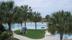 A pool area with a sign indicating no lifeguard on duty, surrounded by palm trees and lounge chairs. - Large Deck with Awesome Ocean & Marsh View! Free WiFi! Free Hunting Island pass! (St. Helena Island)